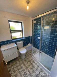 New bathroom installation with new shower, toilet, sink and blue tiling