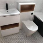 Modern bathroom interior designed by a professional bathroom fitter, featuring a white sink vanity and toilet suitable for disabled access.