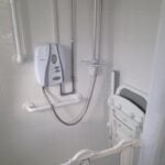 Accessible bathroom installation equipped with handrails and a shower seat for safety and assistance.