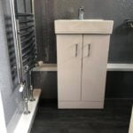 Modern bathroom interior with a white vanity cabinet, designed as a disabled bathroom, and a glittery wall.
