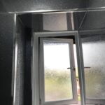 Frosted glass window in a disabled bathroom with gray speckled walls, providing privacy while allowing light to enter.