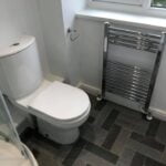 Modern bathroom interior featuring a disabled toilet next to a window and a towel radiator.
