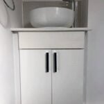 White bathroom vanity with a round vessel sink and modern faucet, designed for exquisite bathroom installations.