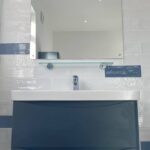 Modern bathroom sink with blue and white tiles, a wall-mounted mirror, and optimized for disabled bathroom installation.
