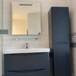 Modern bathroom interior with a wall-mounted sink, mirror, and a tall storage cabinet following professional bathroom installation.
