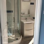 A modern disabled bathroom with a corner shower enclosure and a vanity unit.