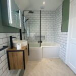 Modern bathroom with white subway tiles, walk-in shower, and a wooden vanity, designed for disabled access.
