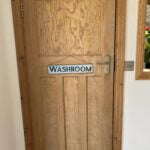 A wooden door with a "bathroom" sign and a silver handle, indicating an accessible design for disabled users.