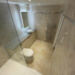 Modern disabled bathroom with a shower enclosure, toilet, and towel radiator.