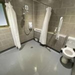 Accessible bathroom for the disabled with grab bars, a walk-in shower area, and a mounted shower seat.