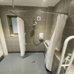 Accessible disabled bathroom with a walk-in shower and handrails.