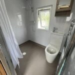 A modern disabled bathroom with a walk-in shower, toilet, and a mirror cabinet.