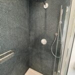 Modern bathroom design featuring mosaic tiles and dual showerheads.
