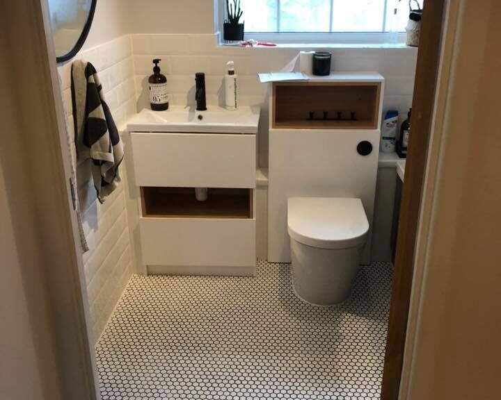 A small, modern bathroom with a white vanity, toilet, and hexagonal tile flooring designed for easy disabled access.