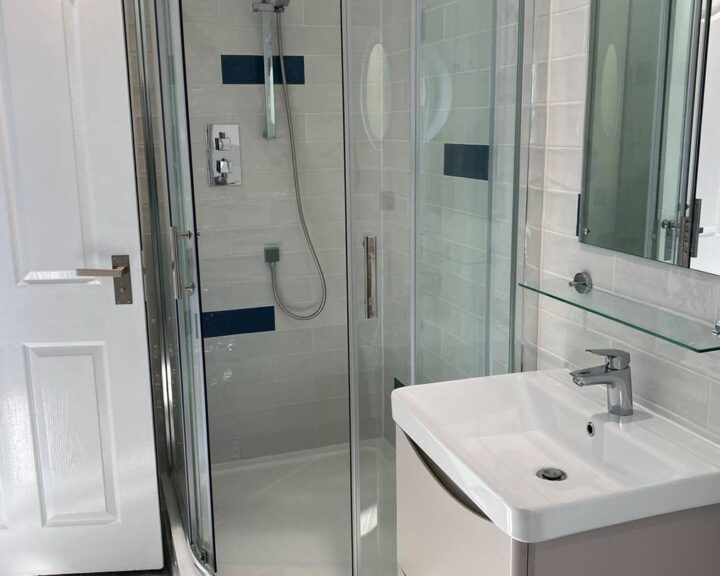 A modern bathroom design featuring a glass shower enclosure and a white pedestal sink.