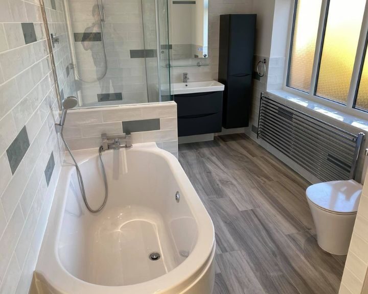 Modern bathroom interior with a freestanding bathtub, glass shower enclosure, vanity unit, toilet, and features suited for a disabled bathroom.