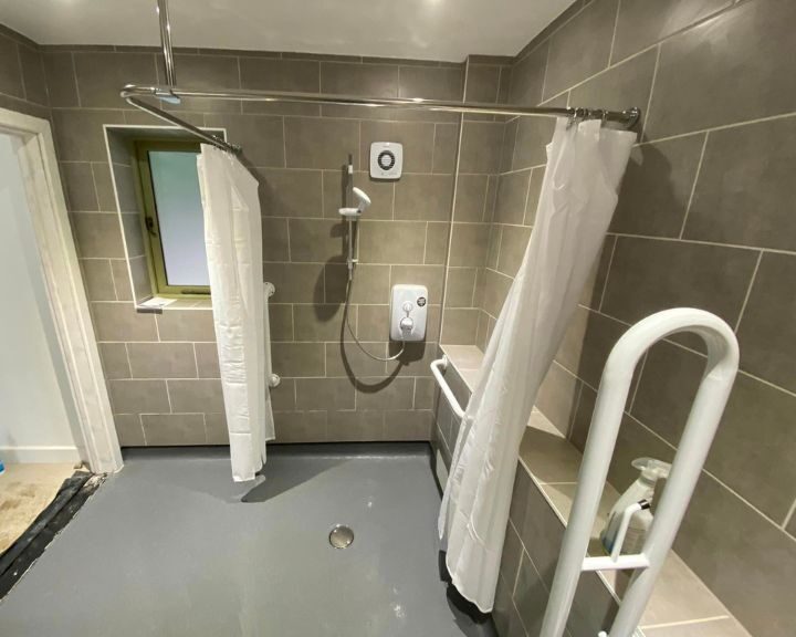 A modern disabled bathroom with a walk-in shower area and grab bars for safety.