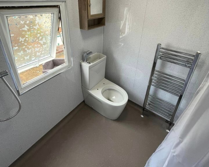 Modern disabled bathroom with an open window, featuring a white toilet and a radiator.