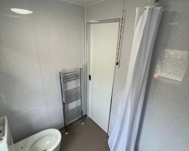 Interior of a modern, disabled bathroom with a shower, toilet, and towel rack.