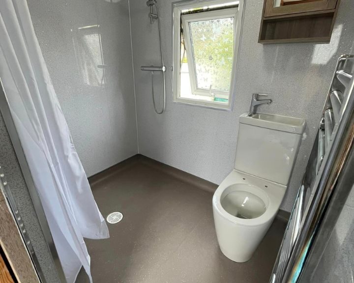 A modern bathroom design with a white toilet, walk-in shower, and gray flooring.